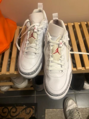 Vita Air Jordan sneakers med röd logga  - Säljer ett par vita Air Jordan sneakers med klassisk röd Jumpman-logga på plösen och grått elefantmönster runt tån och hälen. Skorna har vita snören, meshpaneler på sidan och detaljer i läder. Perfekta för dig som gillar streetwear och snygg design. Pris går att diskuteras, använda 2 gånger. Kvitto och låda finns 