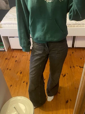 Svarta vida  jeans med medelhög midja - Säljer ett par svarta jeans med en vid passform och medelhög midja. Jeansen har klassisk femficksdesign och stängs med dragkedja och knapp. Perfekta för en avslappnad och trendig stil.