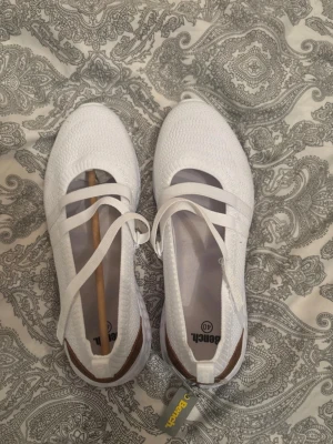 Vita ballerinaskor från Bench - Snygga vita ballerinaskor från Bench med stickad ovandel och elastiska band över foten. Skorna har en sportig sula med struktur och en brun detalj vid hälen. Perfekta för dig som gillar en clean och modern look. För fler bilder/information skriv gärna, priset kan justeras 🤗❤️