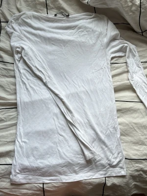 Vit långärmad topp i bomull - En enkel och stilren vit långärmad topp i mjuk bomull. Modellen har rund halsringning och en normal passform, perfekt att matcha med jeans eller kjol. Passar dig som gillar basic-plagg med clean look.