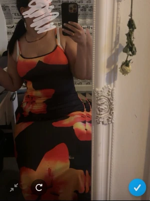 Långklänning med stora blommor - Säljer en långklänning med stora blommor i orange, rött och gult på svart botten. Klänningen har smala axelband och figurnära passform. Perfekt för dig som vill sticka ut med färg och mönster. Den passar både m o L och xl väldigt bra material, pris går och diskuteras 