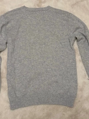 Ljusgrå kashmirtröja från John Henric - Snygg ljusgrå stickad tröja från John Henric. Tröjan har rund halsringning, långa ärmar och ribbade muddar vid ärmslut och nederkant. Perfekt basplagg i mjukt material som passar till allt.