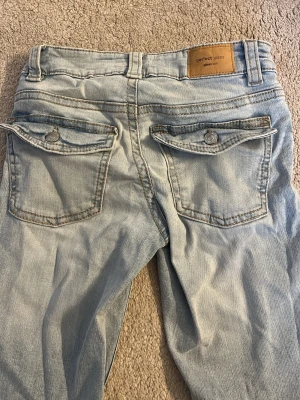 Ljusblå bootcut jeans från Gina  - Säljer ett par ljusblå bootcut jeans från Perfect Jeans. Jeansen har två bakfickor med lock och knapp, klassisk femficksmodell och är tillverkade i denim. Perfekta för dig som gillar en avslappnad men ändå snygg stil. Använda max 3 gånger