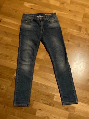 Hansen&jacob - Snygga blå slim fit jeans med lätt slitna detaljer och klassisk femficksdesign. Jeansen har normal midja och smala ben, perfekt för en trendig och avslappnad look. Materialet är denim med stretch för extra komfort.