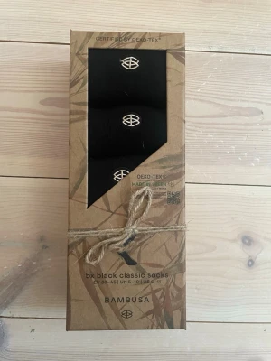 Svarta bambustrumpor från Bambusa - Fempack svarta klassiska strumpor från Bambusa i unisexmodell. Tillverkade av mjuk bambuviskos med förstärkt tå och häl, sömlös design och diskret logga. Strumporna är miljövänliga, luktfria och allergivänliga.