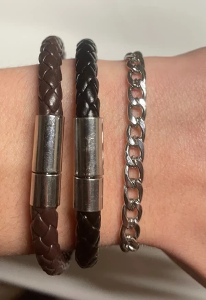 Set med flätade armband och kedja - Säljer ett set med två flätade armband i svart och brunt konstläder med metallås samt ett silverfärgat kedjearmband✅Snygga att bära tillsammans eller var för sig för en stilren look🔥                                Pris var för sig 40 kr st. Tillsammans                     99kr🤝 Skriv i dm för frågor och priset går att diskuteras vid snabb affär!👍🤝