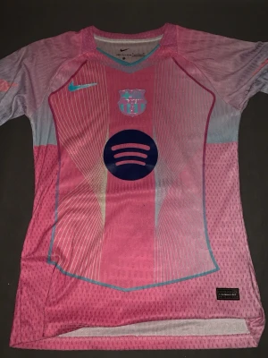 Barca matchtröja rosa Nike - Säljer en FC Barcelona matchtröja i rosa och ljusblått från Nike. Tröjan har klubbmärke och Nike-logga på bröstet samt Spotify-logga i mitten. Sportig design med korta ärmar och ventilerande material, perfekt för fotbollsträning eller match.