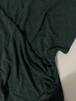 Mörkgrön t-shirt från SHEIN - En enkel mörkgrön t-shirt från SHEIN i mjukt material. T-shirten har korta ärmar och en klassisk passform som funkar till det mesta. Perfekt basplagg för garderoben.