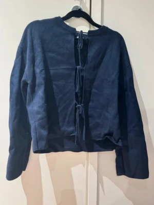 Mörkblå tröja med knytning bak - Mörkblå tröja från GINA TRICOT med öppen framsida och tre knytband längs framsidan. 