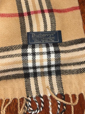 Beige rutig halsduk från Burberrys - Den andra klassiska burrberry halsduken, i den originala färgen. Mycket stilig och perfekt nu när det är extra kallt. Värmer och är extremt skönt. 