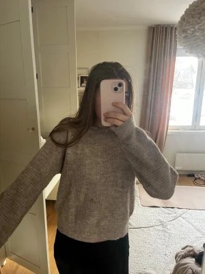 Beige stickad tröja med rund hals - Mysig beige stickad tröja med rund hals och långa ärmar. Tröjan har en rak passform och ribbstickade muddar vid ärmslut och nederkant. Perfekt för lager-på-lager och enkel att matcha med olika outfits.