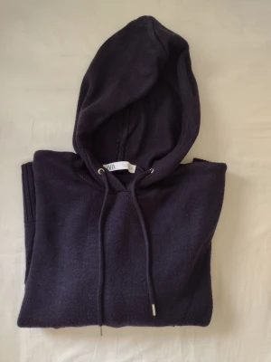 Mörkblå hoodie från zara - Mysig mörkblå hoodie från zara med huva och dragsko. Tillverkad i mjukt stickat material och har en klassisk känguruficka framtill samt ribbade muddar vid ärmslut och nederkant. 
