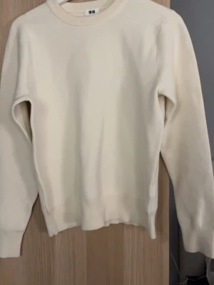 Ljusvit sweatshirt från Uniqlo - En stilren ljusvit sweatshirt från Uniqlo med klassisk rund halsringning och ribbade muddar vid ärmslut och nederkant. Perfekt för en clean och enkel look. Passar till det mesta och är superenkel att matcha.