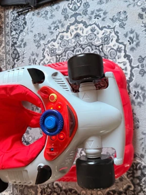 gåstol bil - Säljer en cool gåstol formad som en bil i rött och grått med svarta hjul och blå ratt. Sätet är mjukt och rött, och det finns flera färgglada knappar på instrumentpanelen. Perfekt för små barn 6-9 månader som vill utforska hemmet på ett roligt sätt 