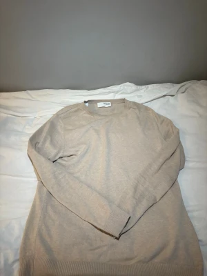Beige stickad tröja Selected Homme - Snygg beige stickad tröja från Selected Homme. Tröjan har rund halsringning, långa ärmar och ribbade muddar vid ärmslut och nederkant. Perfekt basplagg i mjukt material som passar till det mesta.100%bomull. Storlek S men stor i storleken