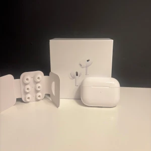 AirPods Pro gen 2  - Säljer ett par vita Apple AirPods Pro med trådlöst laddningsetui. Inkluderar flera silikonproppar i olika storlekar för perfekt passform. Snygg och stilren design i blankt plastmaterial. Perfekta för musik, samtal och träning.