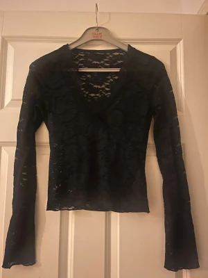 Svart spetsblus från Gina Tricot - Säljer en svart långärmad spetsblus från Gina Tricot. Blusen har v-ringning och är helt i genombruten spets med blommigt mönster. Perfekt att styla lager på lager eller med ett linne under. Supersnygg och trendig topp för dig som gillar detaljer.