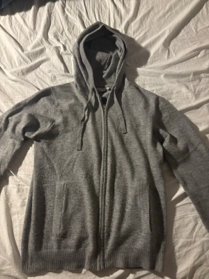 Grå stickad hoodie från RYVLS  - Stickad zip hoodie från RYVLS. Bekväm modell i mjukt stickat material med huva och hel dragkedja framtill. Storlek 170–176 och passar bra på mig som är 174 cm. Nästan oanvänd och i mycket gott skick. Stilren och lätt att matcha till vardags. Pris ej hugget i sten!