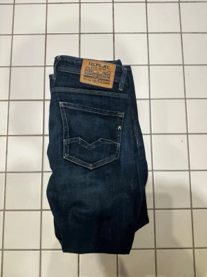 Mörkblå jeans från Replay - Snygga mörkblå jeans från Replay med klassisk femficksdesign och kontrastsömmar. Jeansen har raka ben och en tydlig Replay-lapp bak i midjan. Materialet är denim i bomull med lite stretch för extra komfort. Perfekta för en avslappnad och trendig look.