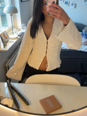 Vit paljettkofta med vida ärmar - Vit blus passar perfekt för fest aldrig använd prislapp säljer då ja inte riktigt tyckte de va min stil köpt på Gina tricot storlek xs