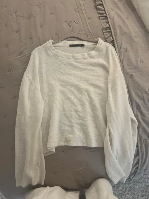 Vit croppad stickad tröja  - Vit stickad tröja med croppad passform och rund halsringning. Tröjan har långa ärmar och är tillverkad i ett mjukt, lätt material som passar perfekt till jeans eller kjol.