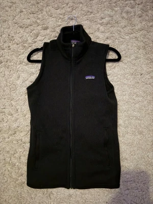 Svart fleeceväst från Patagonia - Svart fleeceväst från Patagonia med dragkedja framtill och två fickor. Klassisk design med hög krage och diskret logga på bröstet. Perfekt lager-på-lager-plagg för kyliga dagar. Den är använd fåtal gånger. Inga defekter alls! Den är som ny. 💪hör av er vid frågor. 