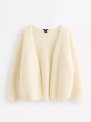 Krämvit fluffig kofta från & Other Stories - Mysig krämvit kofta från & Other Stories med oversized passform och ballongärmar. Koftan är öppen framtill och har en fluffig, mjuk struktur som känns riktigt lyxig. Perfekt för dig som gillar en avslappnad men ändå trendig look.