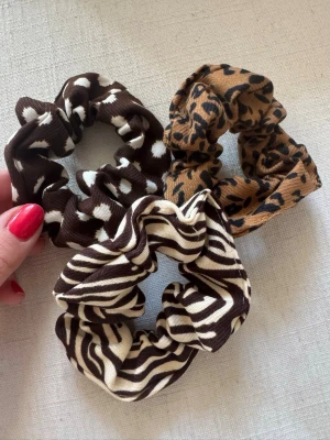 3-pack scrunchies med djurmönster - Säljer ett 3-pack scrunchies i tyg med olika djurmönster: ett i zebramönster, ett i leopardmönster och ett med bruna och vita prickar. Perfekta för att piffa till håret och ge en trendig touch till din look. Har bundlerabatt vid köp av fler varor🥰