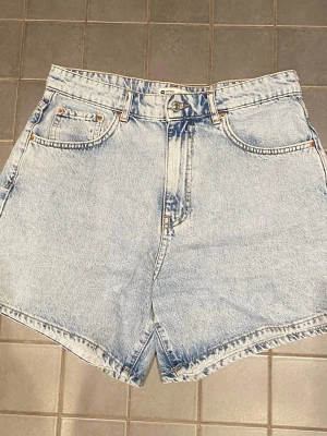 Ljusblå denimshorts från Gina Tricot - Lljusblå denimshorts från Gina Tricot med hög midja. Shortsen har bälteshällor, knappgylf och raka ben. Perfekta för sommaren❣️☀️