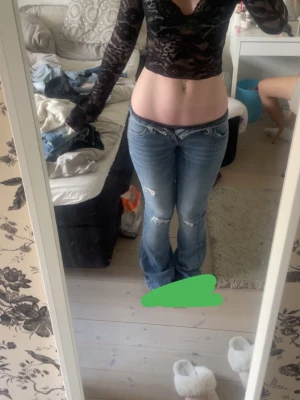 Blå low waist bootcut jeans - Säljer ett par blå bootcut jeans med slitningar och hål på låren och knäna. Jeansen har låg midja och klassisk femficksdesign. Perfekta för en avslappnad och trendig look. Materialet är denim i bomull. Från Gina young 14+ i strl xs