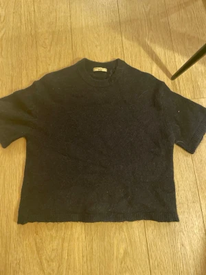 Mörkblå stickad tshirt Gina tricot - Mörkblå stickad tröja från Gina Tricot i kortärmad modell. Tröjan har rund halsringning och är tillverkad i ett mjukt, lite tjockare material. Perfekt för lager-på-lager och en stilren look.