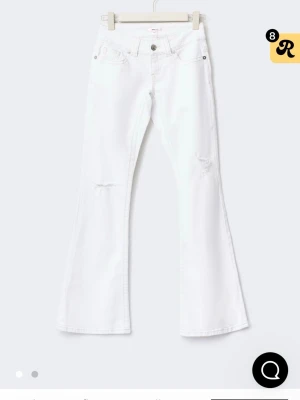 Vita bootcut jeans med slitningar - Säljer ett par vita bootcut jeans med lätt slitna detaljer vid knäna. Jeansen har klassisk femficksdesign, låg midja och vida ben. Perfekta för dig som gillar en retrostil med modern twist.