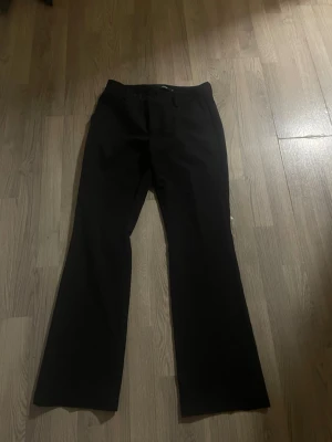 Svarta utsvängda kostymbyxor - Säljer ett par svarta kostymbyxor med utsvängda ben och de går under naveln. använd fåtal gånger