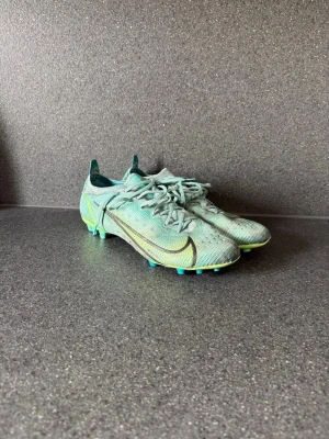Nike Mercurial  fotbollsskor - Säljer ett par Nike Mercurial fotbollsskor för spel på konstgräs för att dem inte används längre. Dem är lite använda men har mycket kvar att ge. Lite sönder/slitna där bak vid hälen(se sista bilen) men de påverkar ingenting när du spelar, använt dem i några månader när dem va så men kände ingen skillnad.