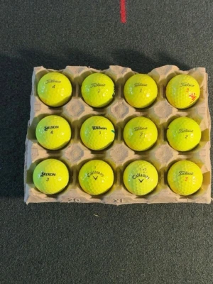 Gula golfbollar  - Säljer ett set med 12 stycken gula golfbollar från märken som Titleist, Callaway, Srixon och Wilson. Bollarna är förpackade i en äggkartong och har klassisk rund form med dimple-mönster. Perfekt för dig som vill ha synliga golfbollar på banan.