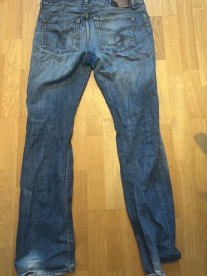 Blå jeans från Calvin Klein Jeans - Snygga blå jeans från Calvin Klein Jeans med klassisk femficksdesign och raka ben. Jeansen har slitningar och tydliga sömmar på bakfickorna samt en läderpatch med logga i midjan. Perfekta för en avslappnad och trendig look.