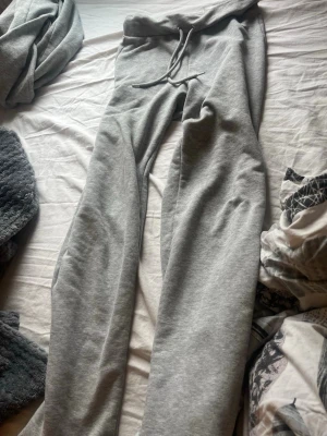Grå mjukisbyxor med dragsko - Säljer ett par klassiska grå mjukisbyxor med resår i midjan och dragsko. Byxorna har raka ben och är gjorda i mjukt bomullsmaterial, perfekta för chill dagar hemma eller när du vill vara extra bekväm.skulle säga att dom mer är xs-s