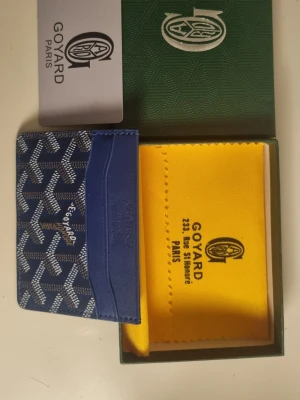 Blå Go4yard korthållare i läder - Snygg blå korthållare från Go4yard med klassiskt mönster i vitt och mörkblått. Tillverkad i exklusivt läder med flera kortfack och elegant logotyp framtill. Perfekt för dig som vill ha en stilren och lyxig accessoar i fickan.