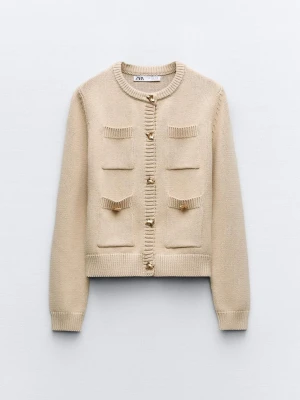 Beige kofta med guldknappar från Zara - Priset kan diskuteras.                                              Stilren beige kofta från Zara med fyra dekorativa fickor framtill och snygga guldknappar. Koftan har rund halsringning, ribbade muddar och är stickad i mjukt material. Perfekt för lager-på-lager och ger en chic look.