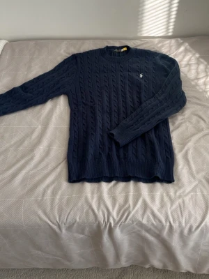 Mörkblå kabelstickad tröja Polo Ralph Lauren - Mörkblå tröja från Polo Ralph Lauren med rund halsringning och klassisk broderad logga på bröstet. Använd cirka 3 veckor påsen finns kvar som äkthet😁