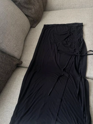Svart lång kjol med knytband - Svart lång kjol i mjukt material med knytband i midjan och en diskret slits framtill. Perfekt för dig som gillar enkel men snygg stil. Passar till många olika looks och är lätt att matcha. Pris går o diskutera 💞💞😊