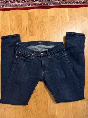 Mörkblå jeans från Polo Ralph Lauren 30/34 - Snygga mörkblå jeans från Polo Ralph Lauren med klassisk femficksdesign och raka ben. Jeansen har diskreta kontrastsömmar och en läderpatch med logotyp på bakfickan. Materialet är robust denim som ger en tidlös look. Sitter slim/rakt 