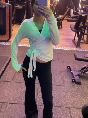 tröja med knytband - Säljer en vit omlott-tröja med långa ärmar och knytband i midjan. Tröjan har en mjuk och stretchig passform, perfekt för att chilla hemma eller i loungen. Materialet känns lätt och bekvämt mot huden. Enkel och stilren design som är lätt att matcha.