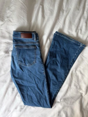 Lågmidjade bootcut jeans  - Blå lågmidjade bootcut jeans från bikbok som är lite slitna mellan skrevet och längst ner vid foten ❤️ passar om man är runt 160 cm lång!