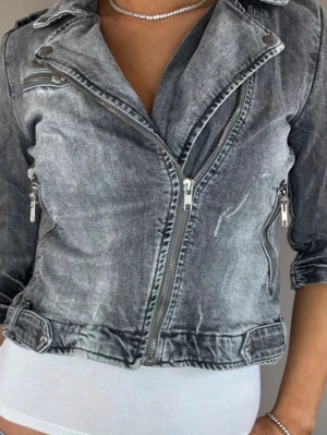 Grå tvättad jeansjacka med dragkedjor - Säljer en grå tvättad jeansjacka med cool bikerstil och flera silverfärgade dragkedjor. Jackan har bred krage och detaljerade sömmar. Den är i M men passar XS/S