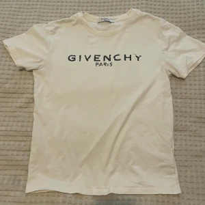 Vit T-shirt från Givenchy Paris - Snygg vit T-shirt från Givenchy Paris med svart tryck framtill. Klassisk rund halsringning och korta ärmar. Perfekt för dig som gillar stilrena designer och exklusiva märken. Materialet känns mjukt och skönt mot huden.