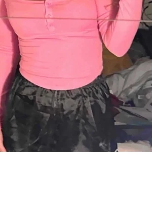 Rosa långärmad topp med knappar - Snygg rosa långärmad topp med rundad urringning och tre knappar framtill. Modellen är figurnära, perfekt att styla med byxor eller kjol. Materialet känns mjukt och stretchigt, vilket gör den bekväm att bära hela dagen.