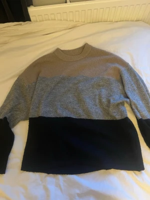 Stickad tröja  - Snygg stickad tröja med breda blockränder i beige, grått och svart. Tröjan har rund halsringning och långa ärmar. 