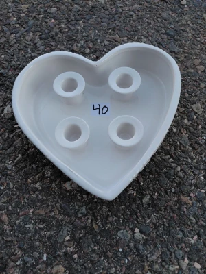 Hjärtaformad vit ljusstake i keramik - Säljer en hjärtaformad vit ljusstake i keramik med plats för fyra ljus. Perfekt som adventsljusstake eller dekoration. Ljusstaken har en stilren design och lätt upphöjda kanter. Passar fint på bordet eller i fönstret.
