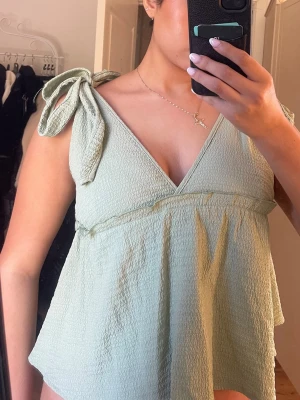 Ljusgrön linnetopp med knytaxlar - Supersöt ljusgrön linnetopp med v-ringning fram och bak samt knytaxlar. Minns ej vilken storlek den är i men troligen s eller m!